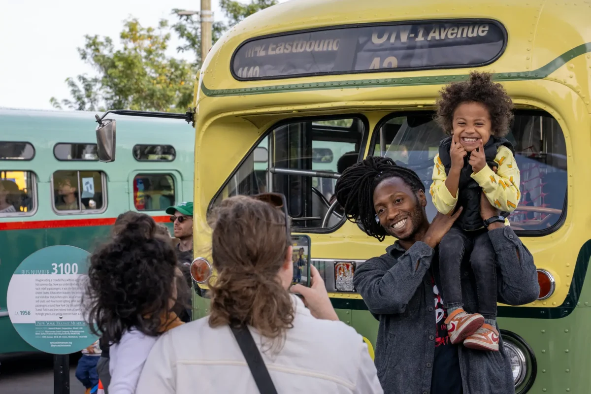 Boy and father in front of green and yellow bus