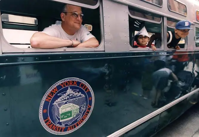 Man and kids looking out window of vintage bus