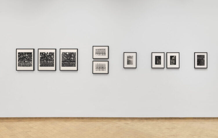 Wall of gallery with framed portraits hung along the wall.