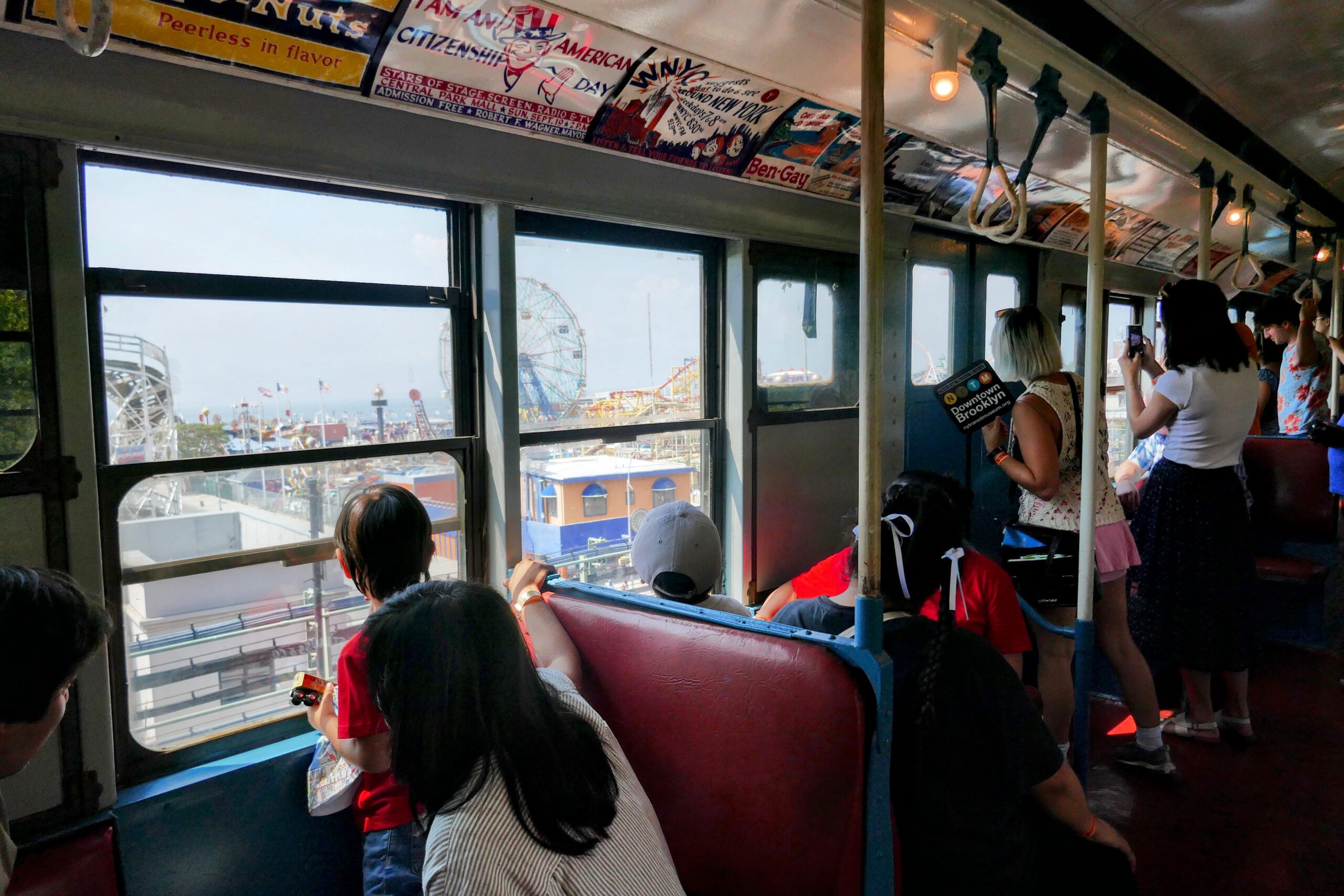 Subway riders view Coney Island attractions through window of vintage train.