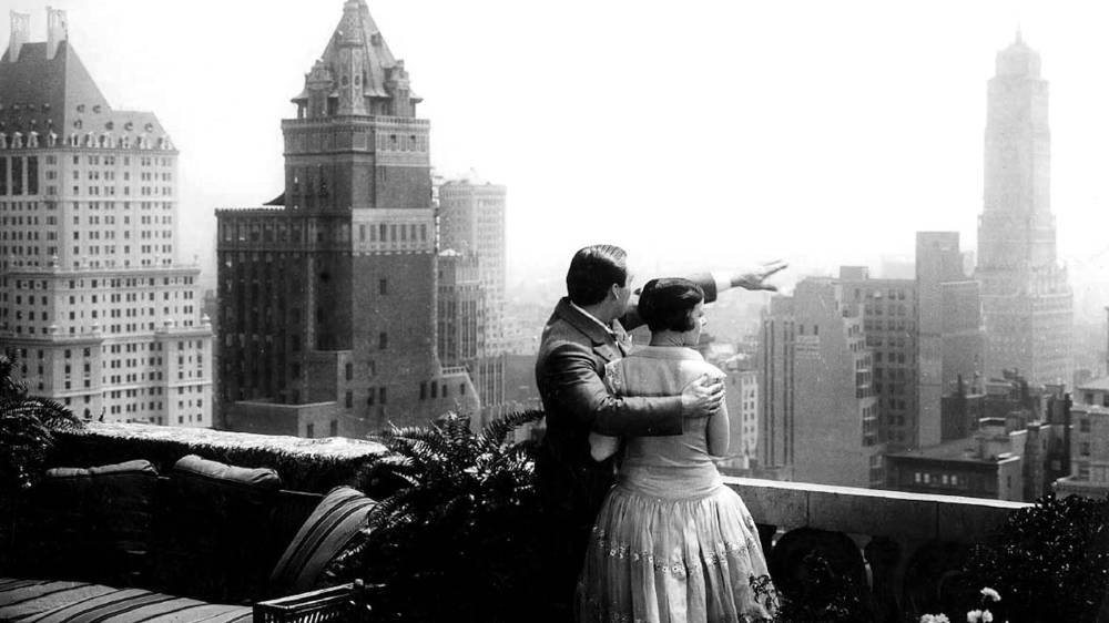 A man and woman look out over New York City's skyline.