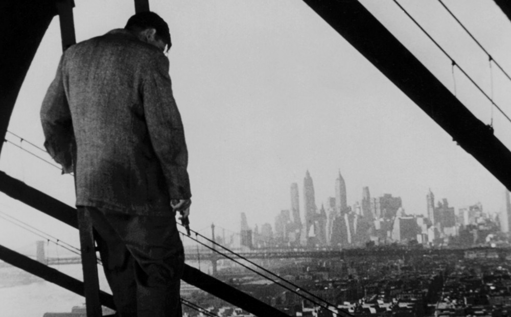 A man overlooks the NYC skyline in a black and white photo.