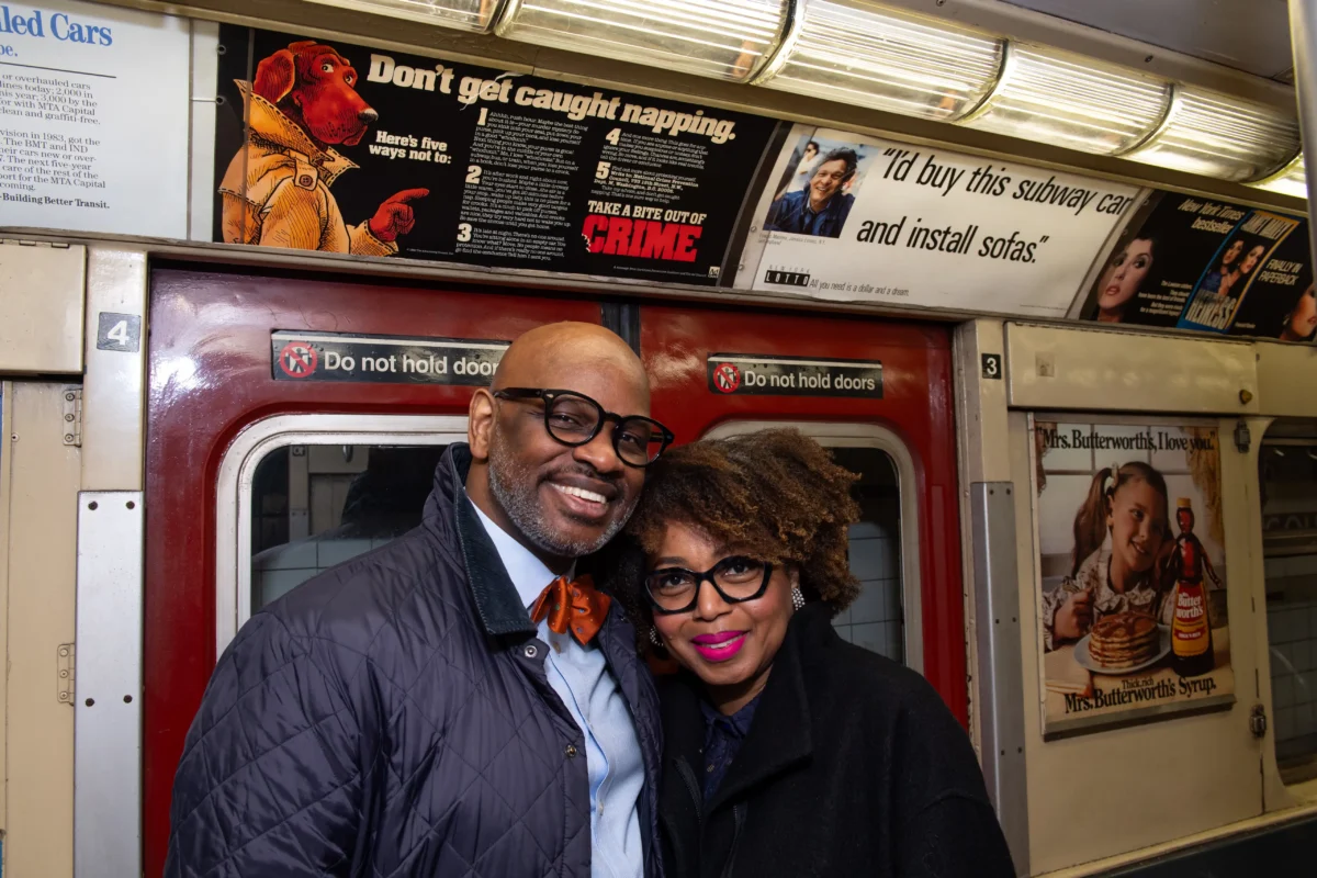 A husband and wife smile on a subway train car.